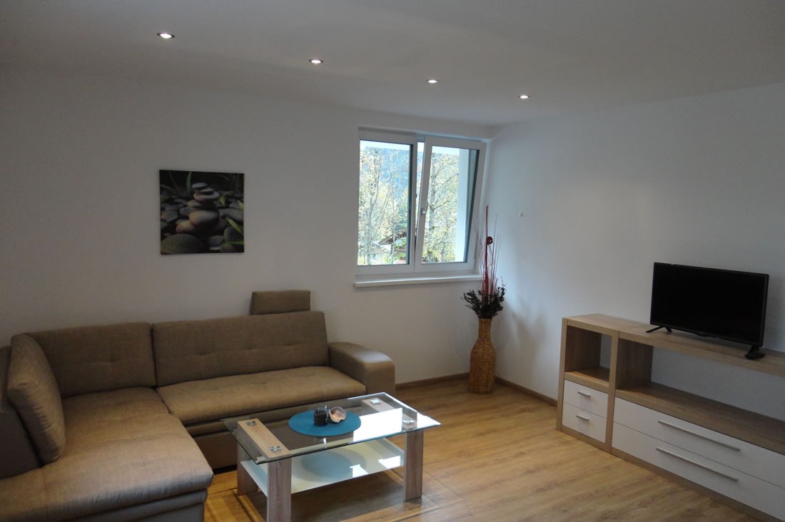 Helles Wohnzimmer mit Flat-TV und gemütlicher Couch